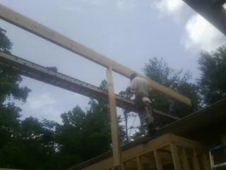 Carpenter setting a ridge beam over a new addition frame — Ice Dam Removal by Roofing Brothers in Perkins