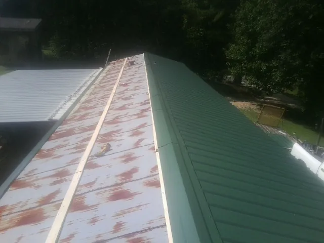 Old rusted panels beside newly installed green metal roofing — Wind Damage Roof Repair by Roofing Brothers in Perkins