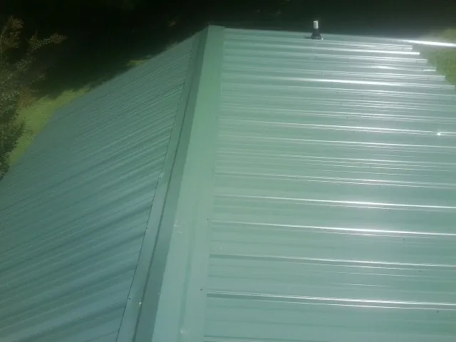 New green metal panels meeting at the ridge of a roof — Flat Roof Repair work by our crew in Perkins