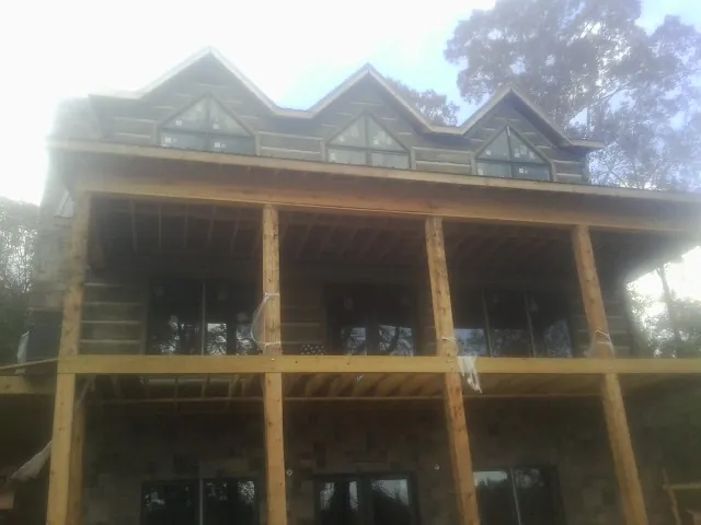 Dormers and porch framing on a large log home under construction — Roof Coating work by our crew in Perkins