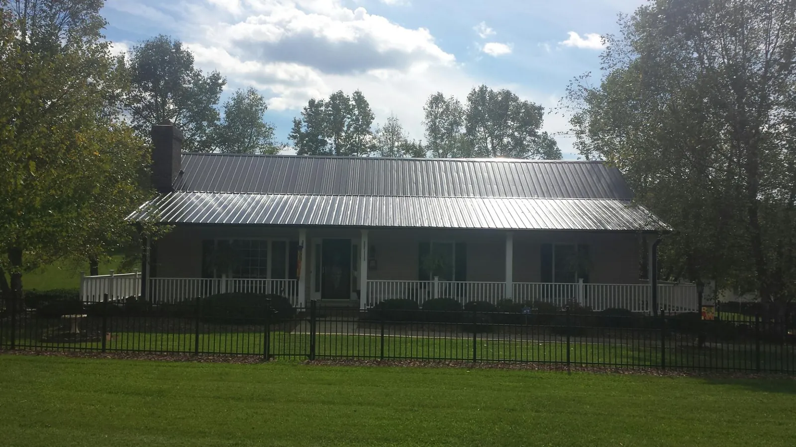 Gray metal roof on a brick ranch with a full width front porch — Gutter Guard Installation work by our crew in Perkins
