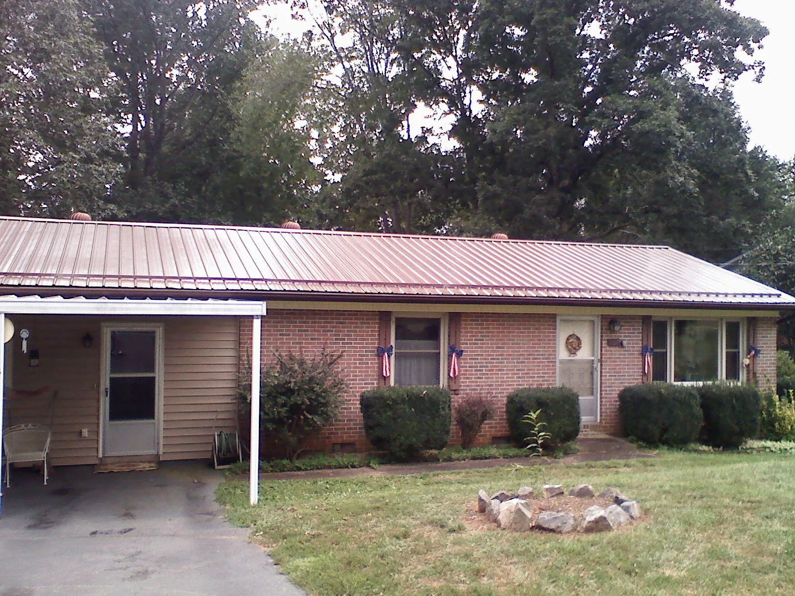 Bronze metal roof and carport on a brick ranch home — Roof Repair work by our crew in Perkins