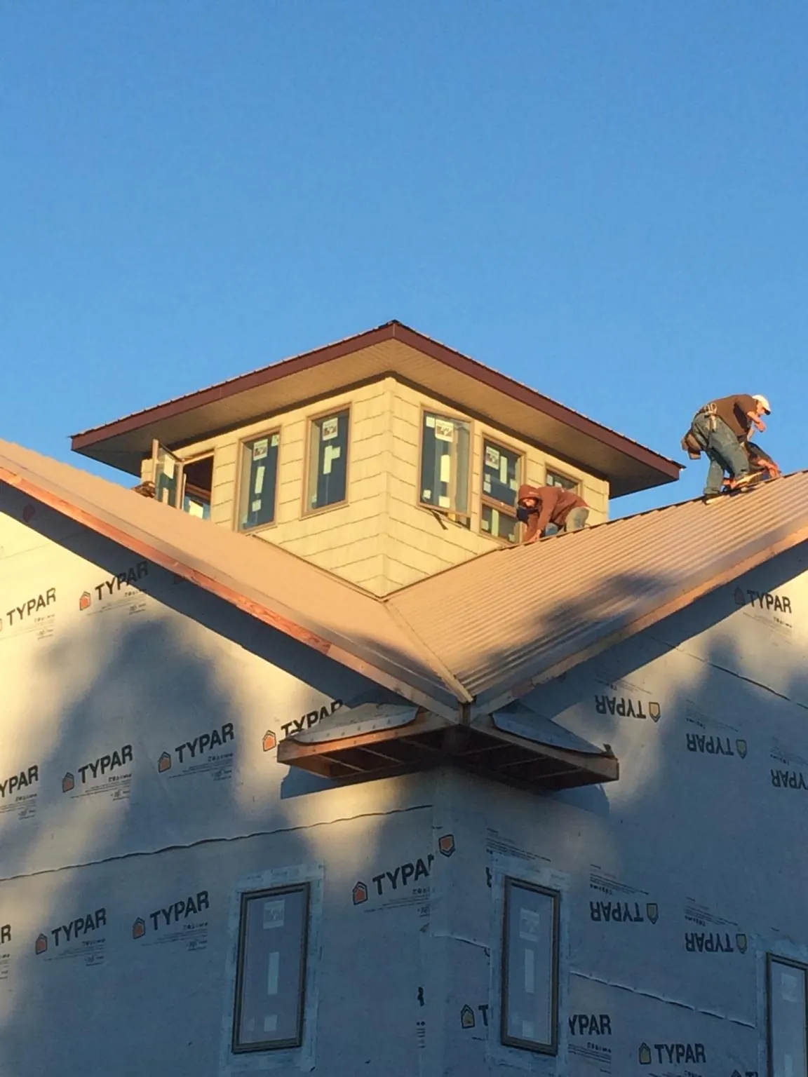 Roofers working around a rooftop cupola on a new metal roof at sunset — Roof Waterproofing in Perkins by Roofing Brothers